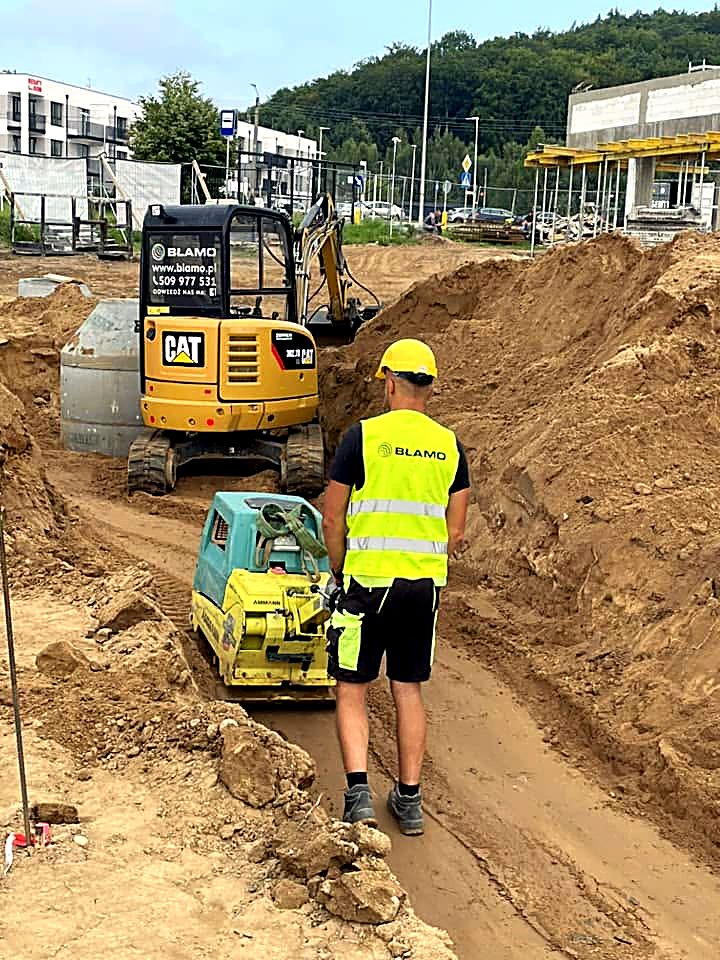 Minikoparka CAT z zagęszczarką na budowie osiedla